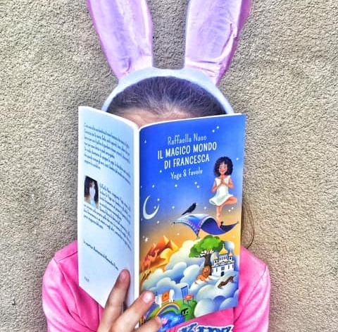 bimba con orecchie da coniglio legge il libro